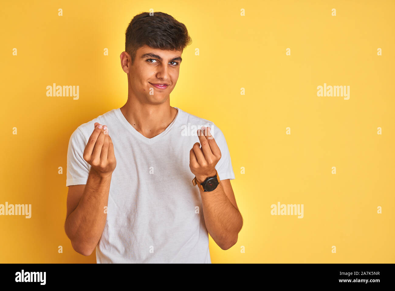 Young indian man wearing white t-shirt standing over isolated yellow ...