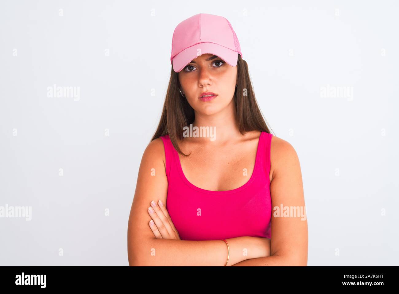 Young beautiful girl wearing pink casual t-shirt and cap over isolated white background skeptic and nervous, disapproving expression on face with cros Stock Photo