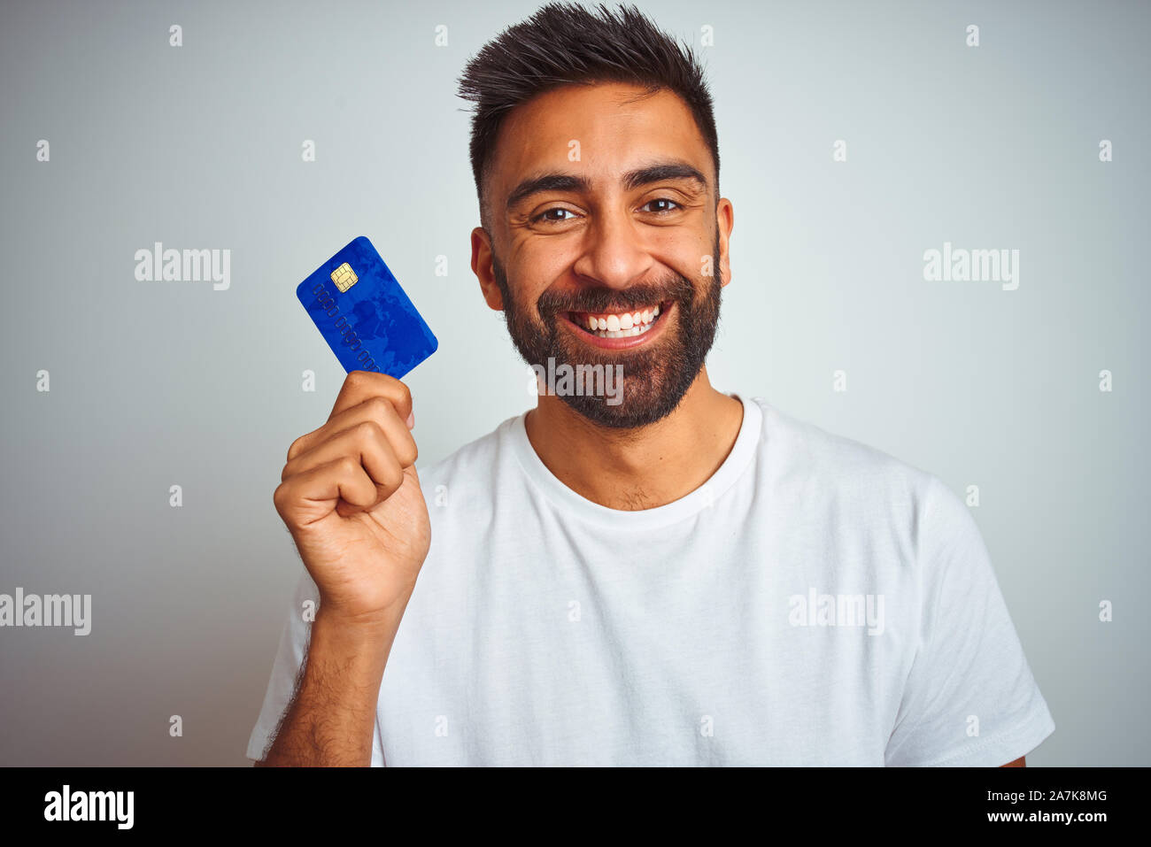 Young indian customer man holding credit card standing over isolated ...