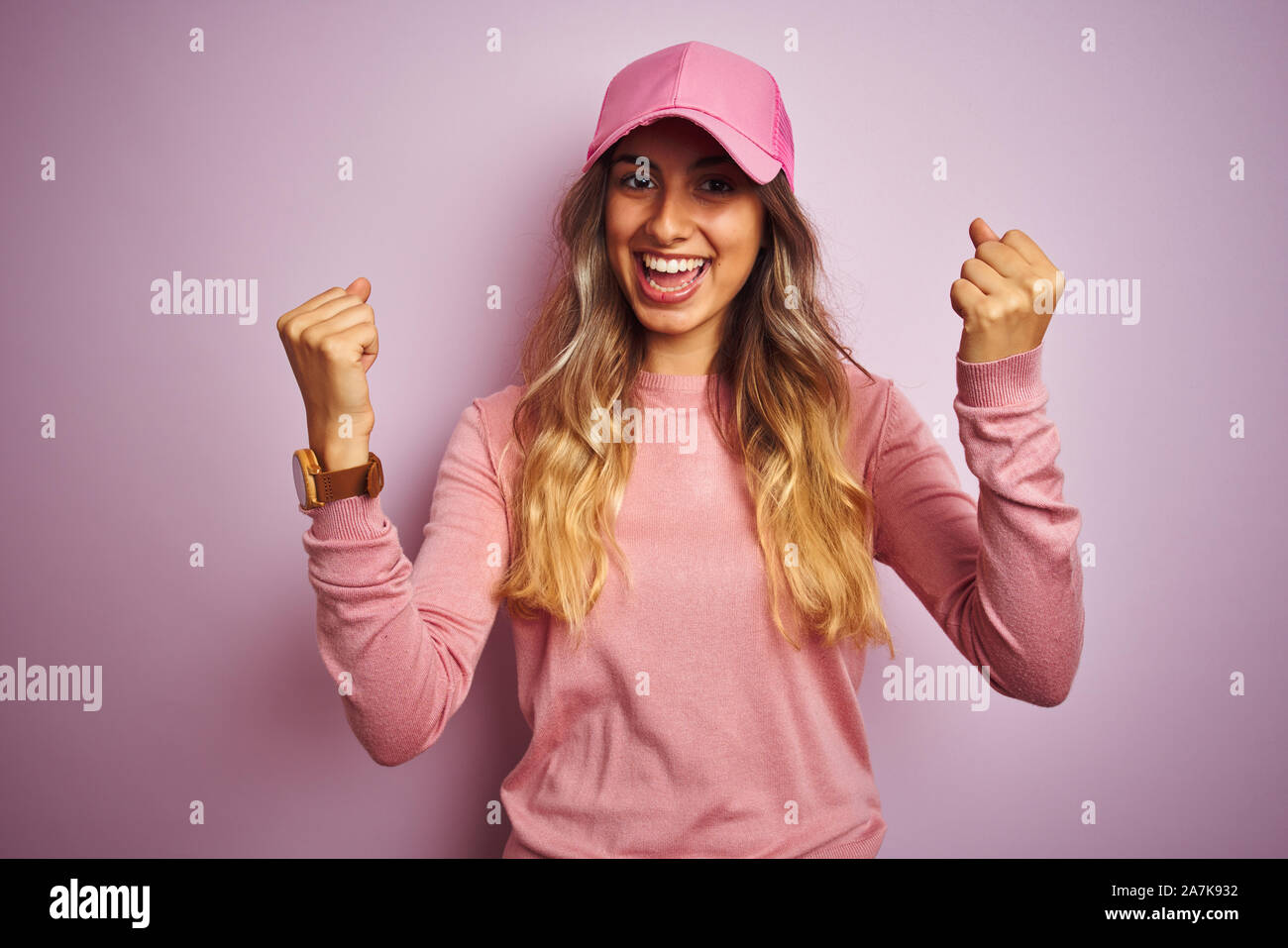 Young beautiful woman wearing cap over pink isolated background celebrating surprised and amazed for success with arms raised and open eyes. Winner co Stock Photo