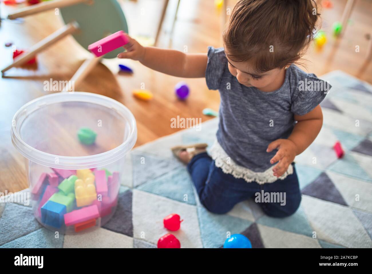 Beautiful toddler saving blocks in plastic cube at kindergarten Stock ...