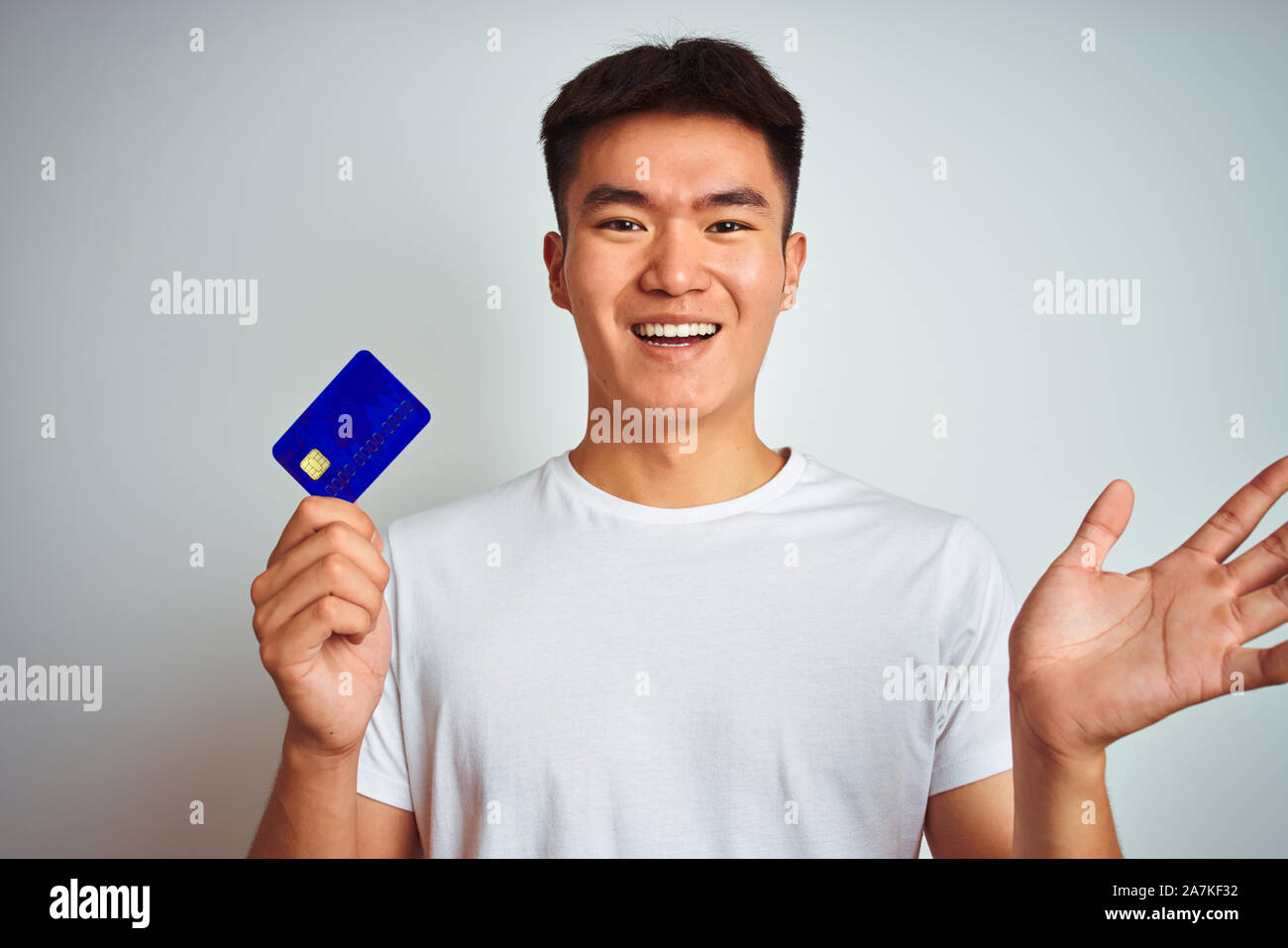 Young asian chinese man holding credit card standing over isolated ...