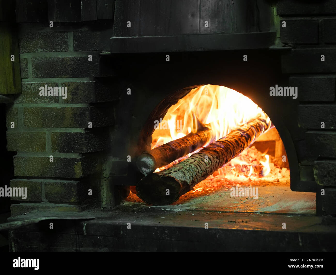 Fire burning with logs inside old fashioned, traditional brick pizza oven. Italy. Stock Photo