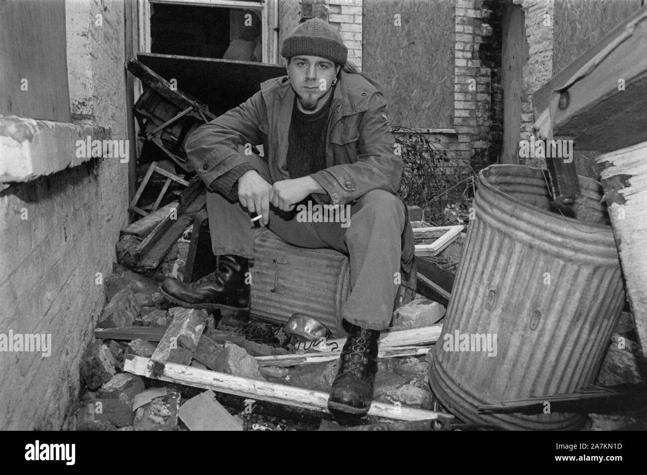portrait of a scruffily dressed smoking young male sitting in the garden of a derelict house 1990s portsmouth england uk Stock Photo