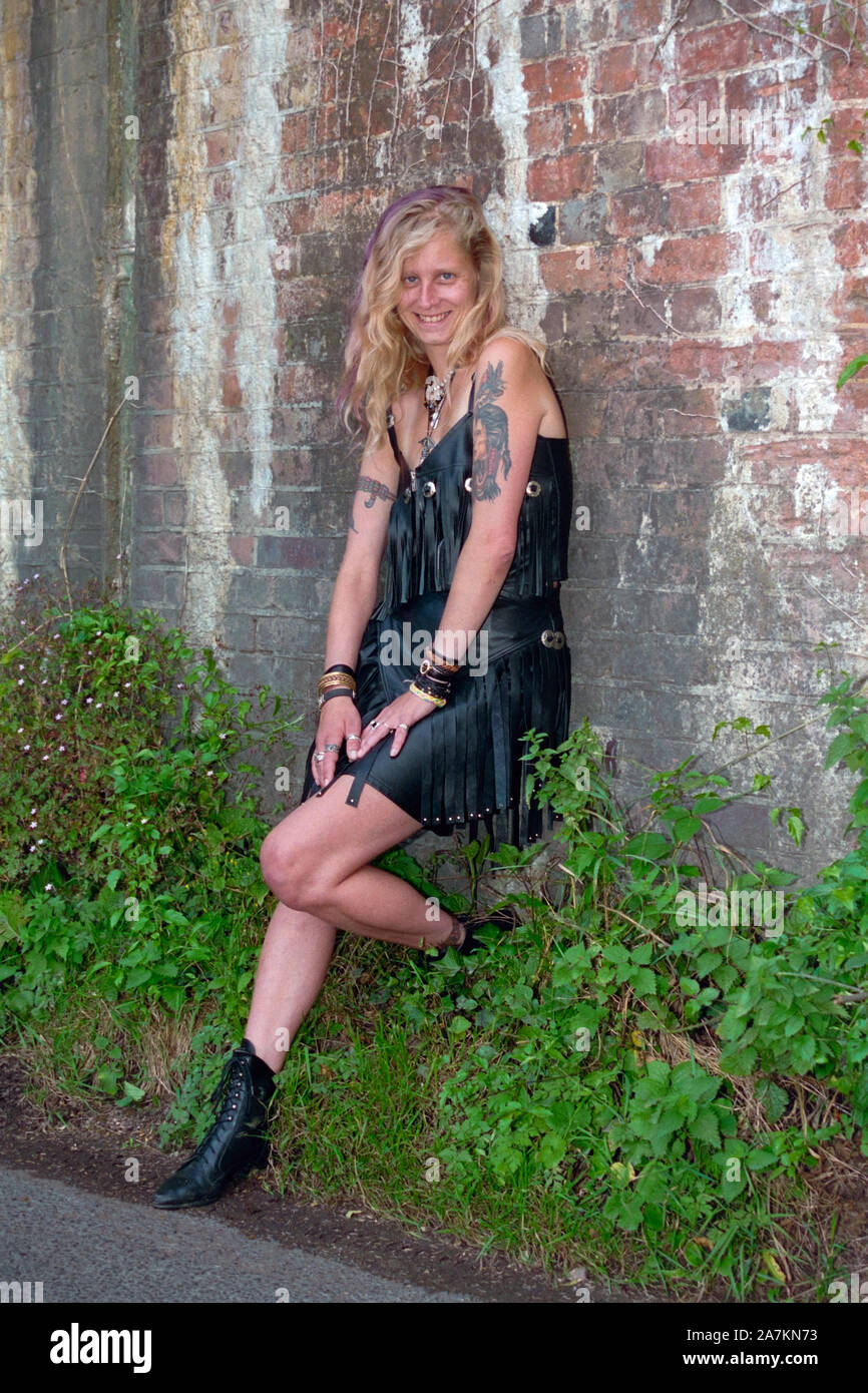 young woman wearing black leather dress standing beneath an old railway  bridge on a rural countryside lane 1990s hampshire england Stock Photo -  Alamy