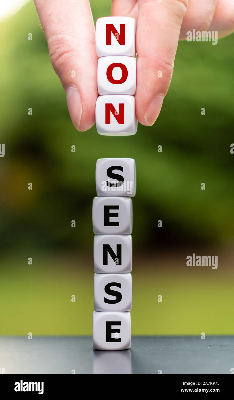 Hand lifts dice and changes the word "nonsense" to "sense". Stock Photo