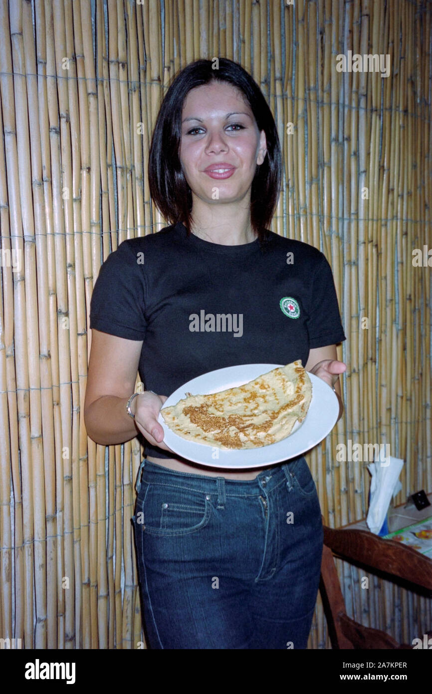 young local female waitress serving a local pancake on a plate in a small restaurant in catania sicily 1990s Stock Photo