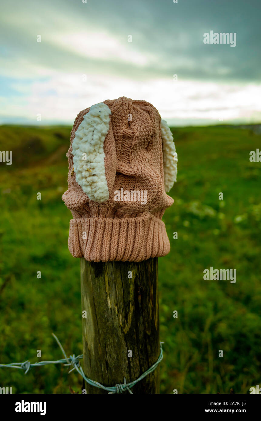 A girls knitted hat that has been lost on a clifftop walk in North Yorshire put on top of a fence post so as to be easily seen. Stock Photo