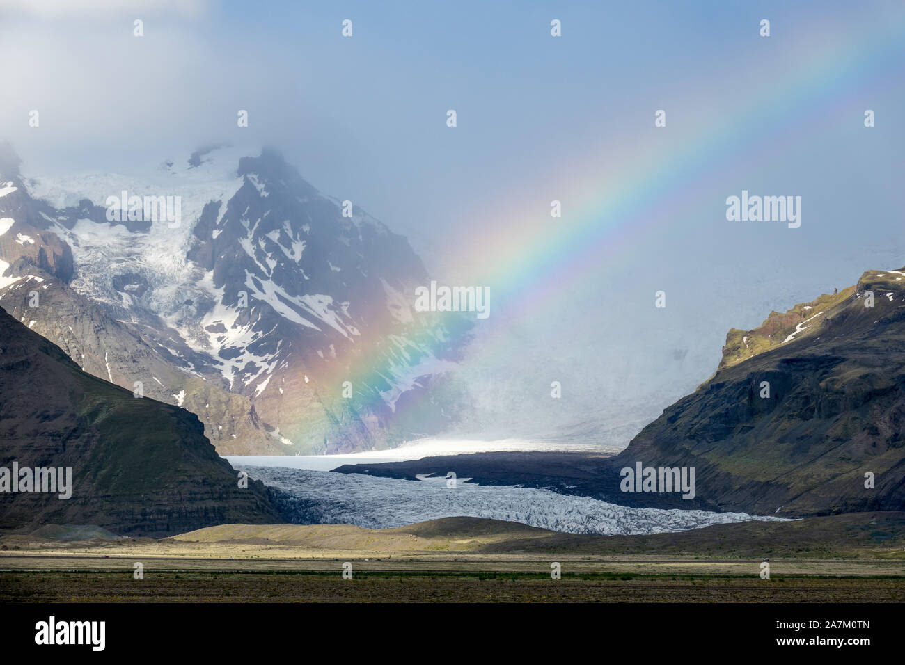 Brilliant and colourful rainbow over Svínafellsjökull glacier and snow-capped mountains, Iceland Stock Photo