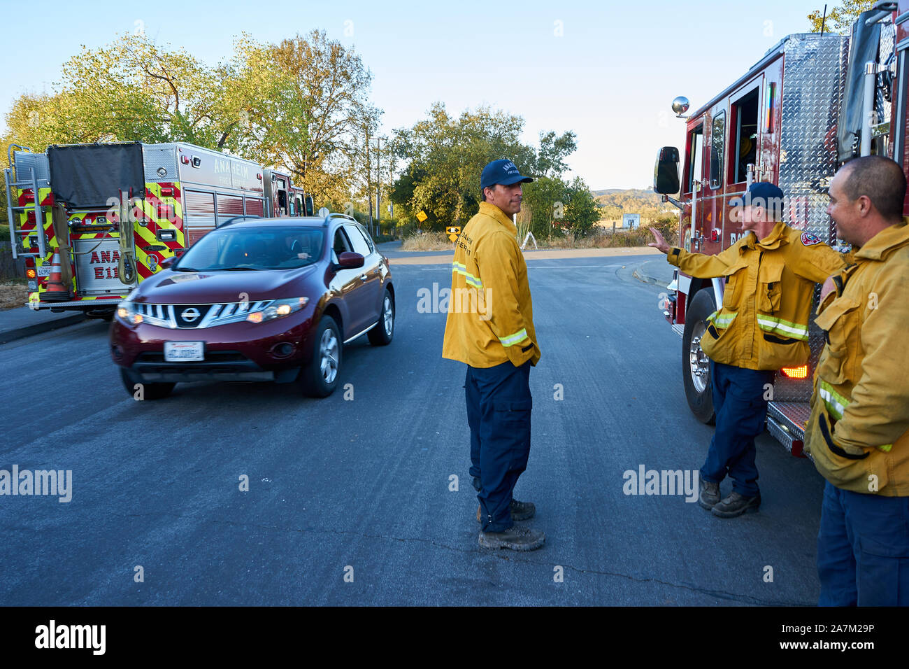 Firefighters rest next red fire truck after battling the Kincade Fire in Windsor, Sonoma County, California. Stock Photo