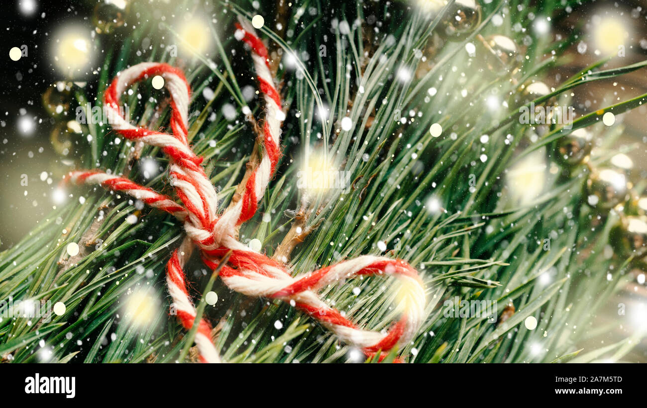 Christmas tree needles with decorations and falling fluffy snowflakes