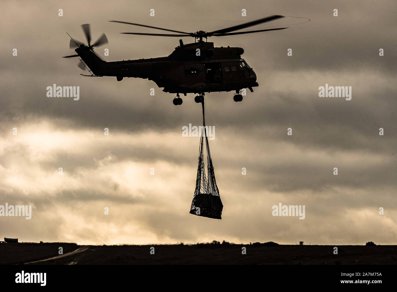 A Puma helicopter of the Royal Air Forces carries an underslung load during  an exercise on Salisbury Plain Training Area Stock Photo - Alamy