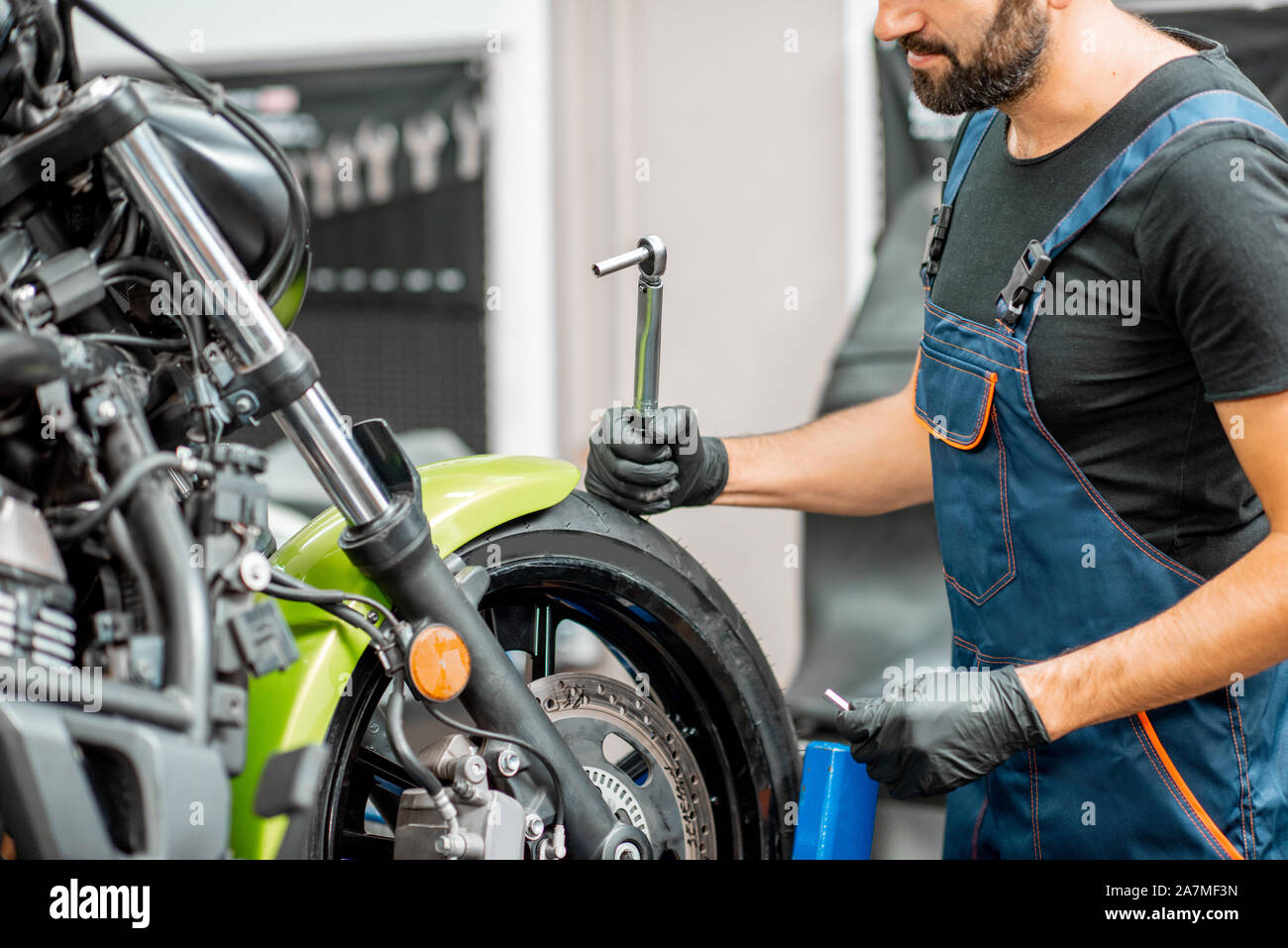 Mechanic in overalls repairing sports motorcycle at the workshop indoors  Stock Photo - Alamy