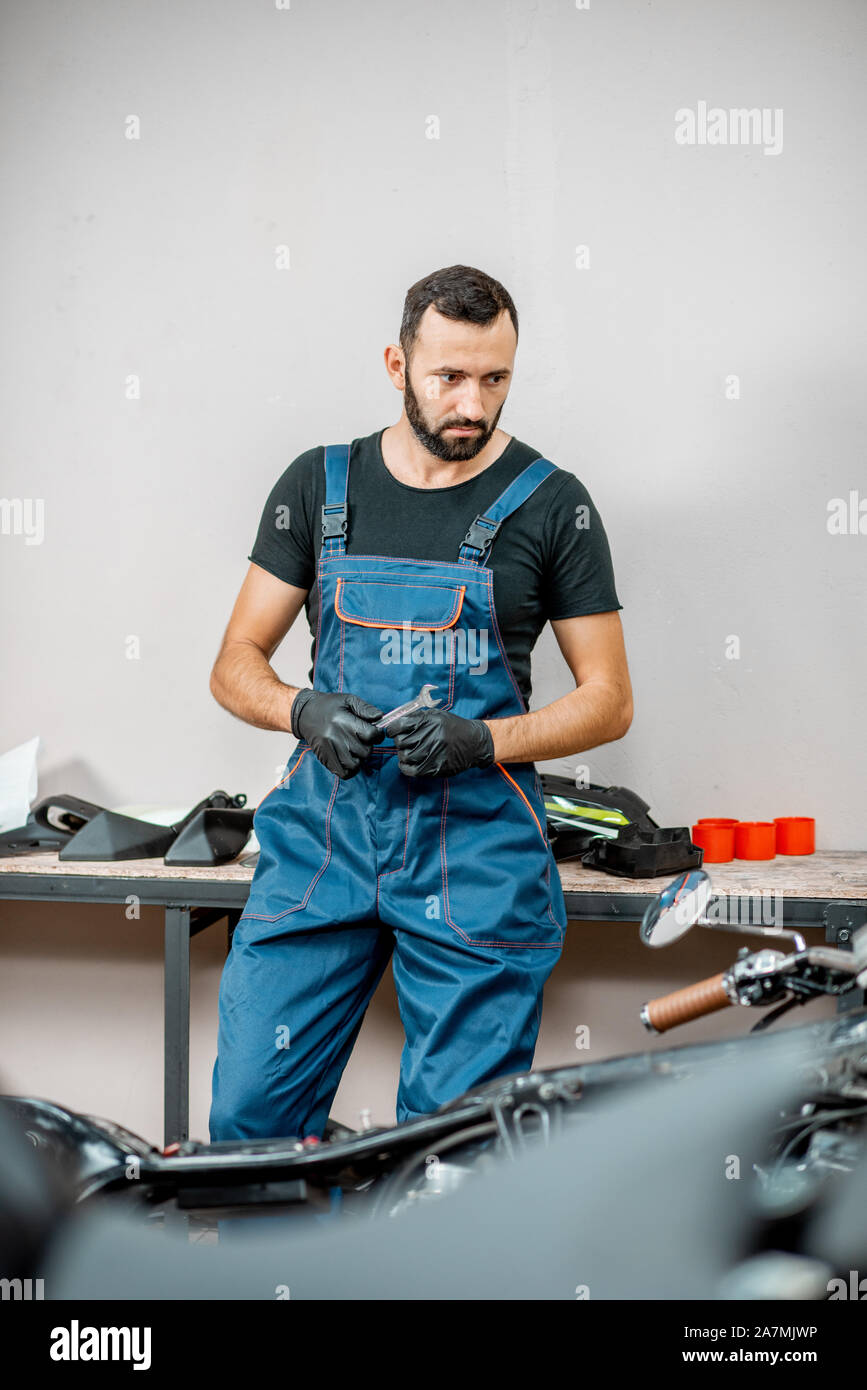 Portrait of a biker or repairman in working overalls standing near the  motorcycle during the repairment in the workshop Stock Photo - Alamy