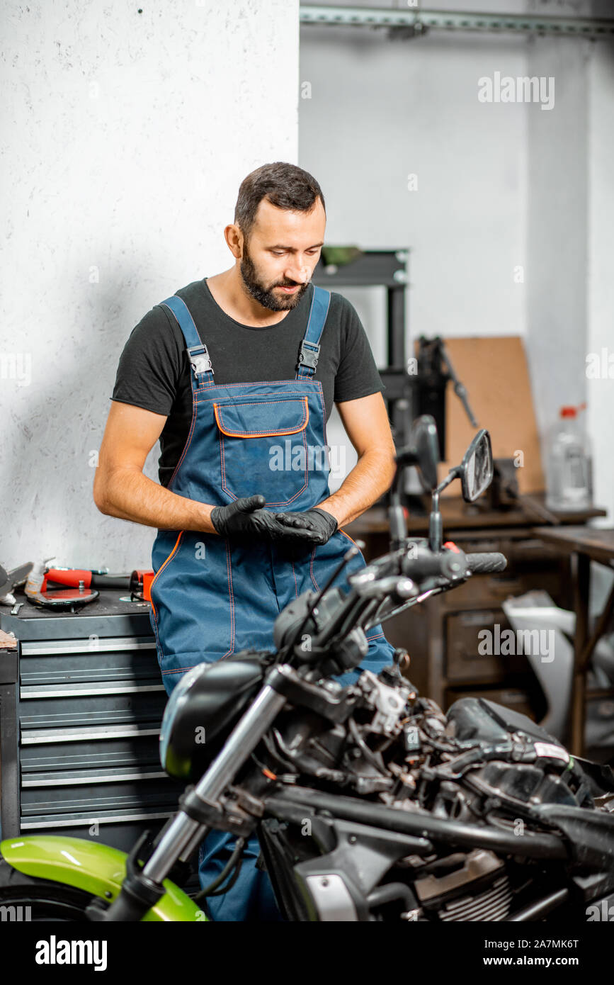Portrait of a biker or repairman in working overalls standing near the ...
