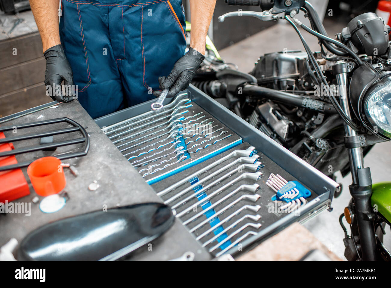 Mechanic getting wrenches from the metal tool box, repairing motorcycle in the workshop, close-up Stock Photo