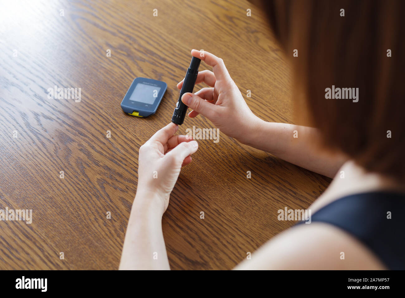 Woman using lancet to take blood sample to check glucose level with