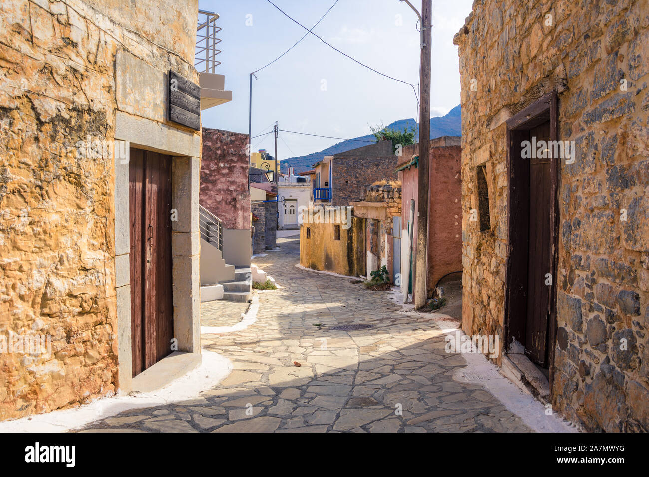 Narrow street with colorful stone houses in the old village of Pano Elounda, Crete, Greece. Stock Photo