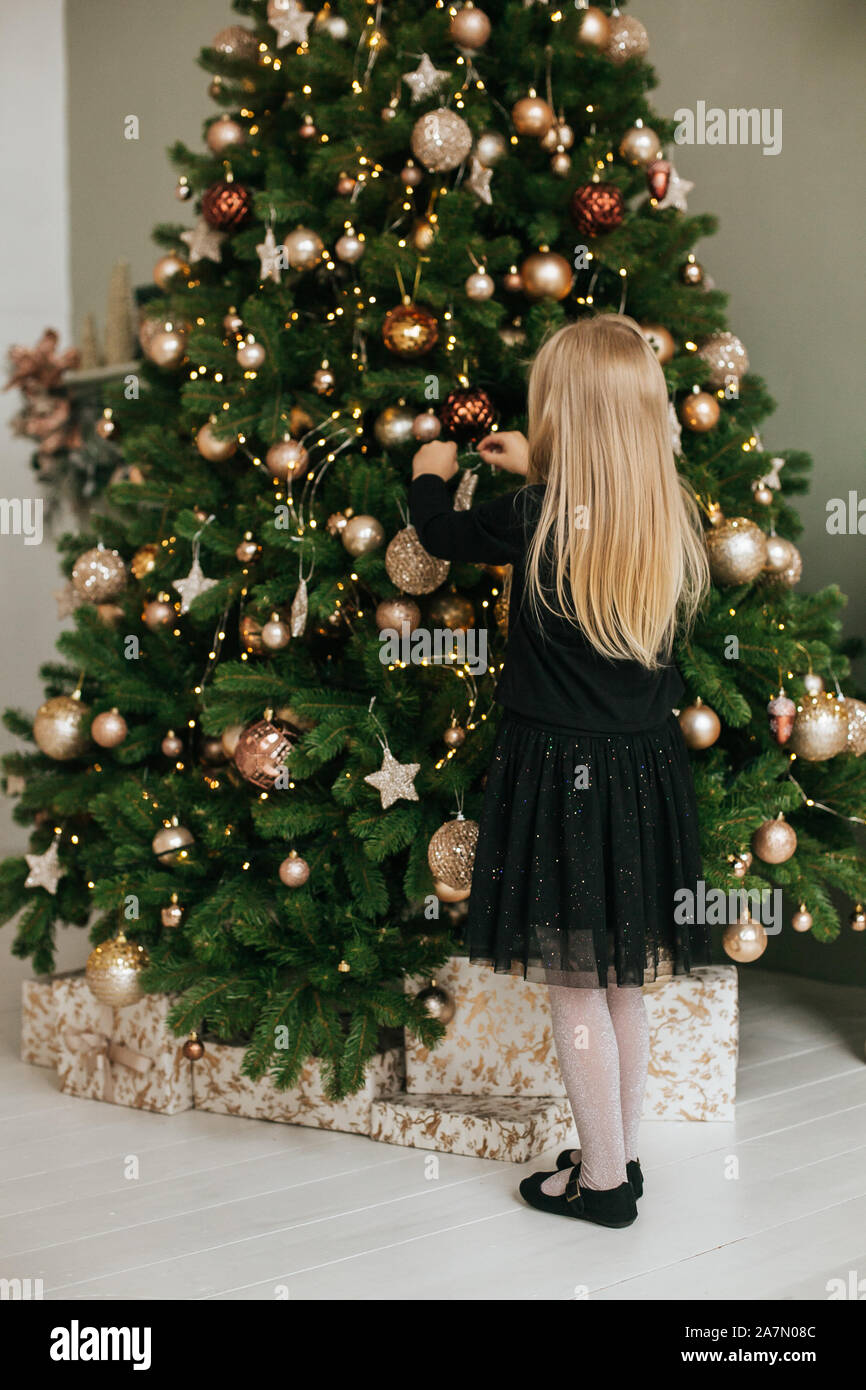 Portrait of a little girl who decorates a Christmas tree Stock Photo ...