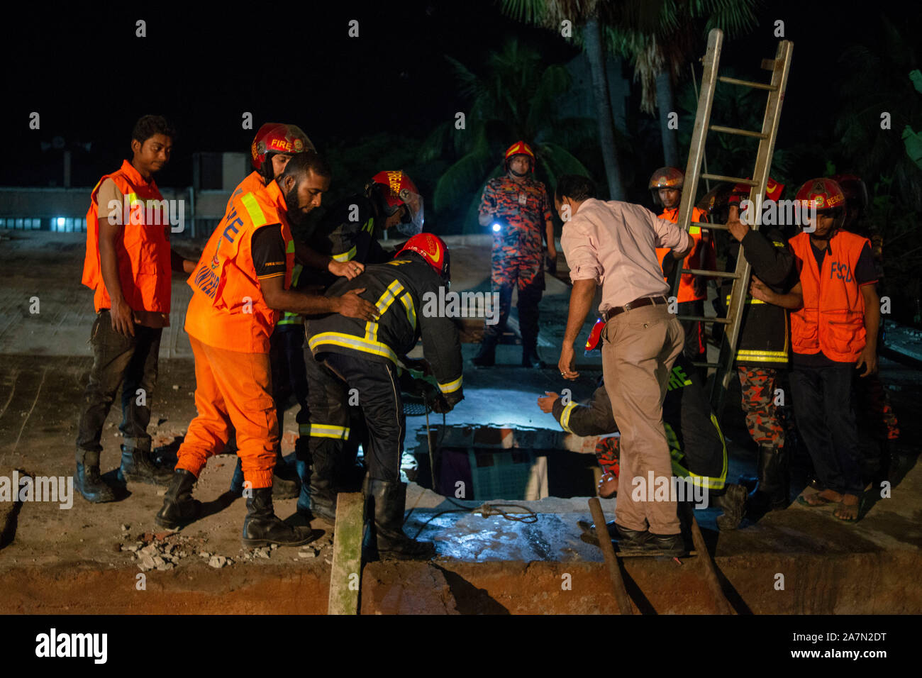 Members of the Fire and Rescue with volunteers looking for a trace of the missing boy.A four storied building collapse beside it's pond in Narayanganj killing a 12 year old boy and one missing, 10 years old. Locals says the building was inappropriate. Stock Photo