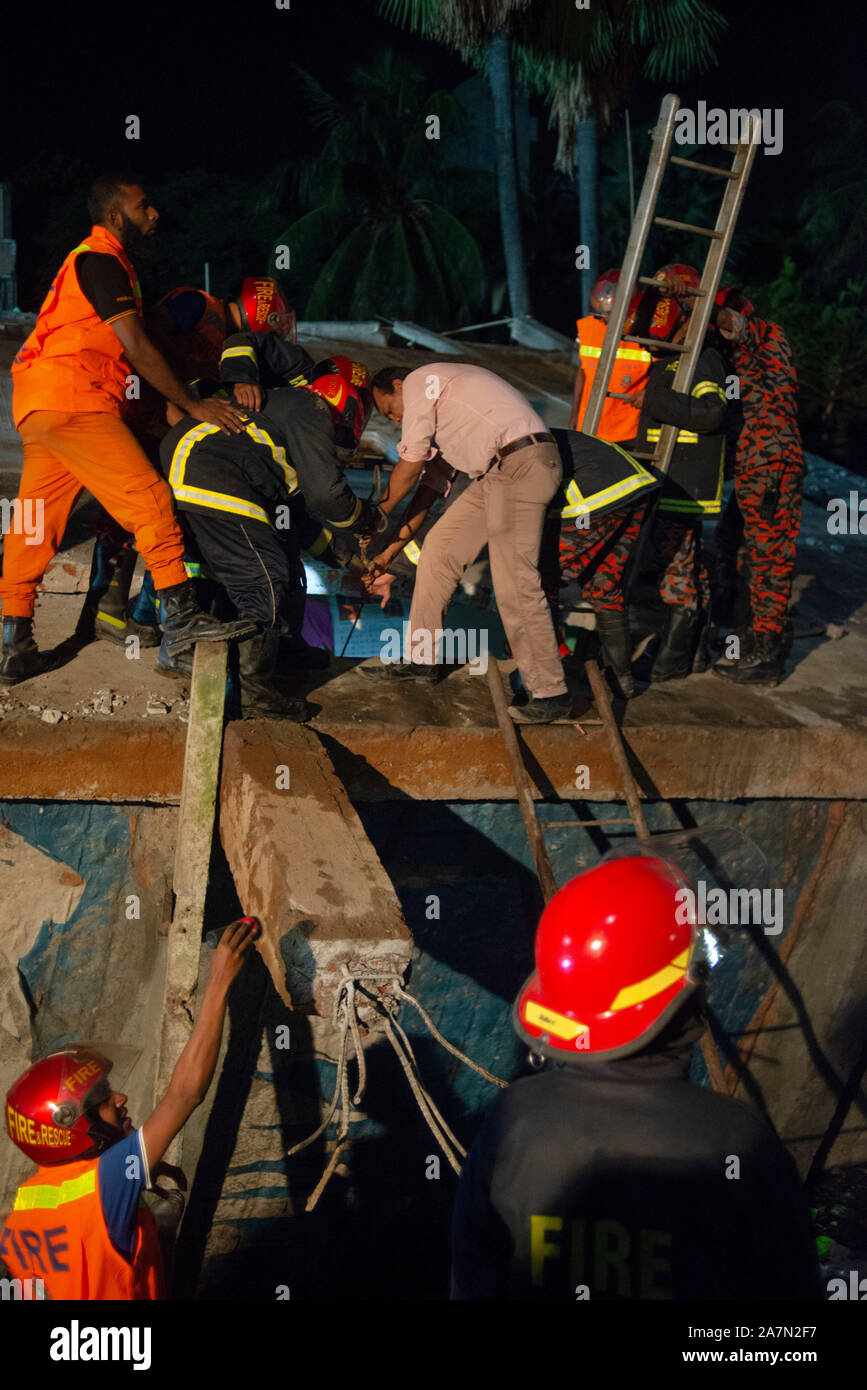 Members of the Fire and Rescue with volunteers looking for a trace of the missing boy.A four storied building collapse beside it's pond in Narayanganj killing a 12 year old boy and one missing, 10 years old. Locals says the building was inappropriate. Stock Photo