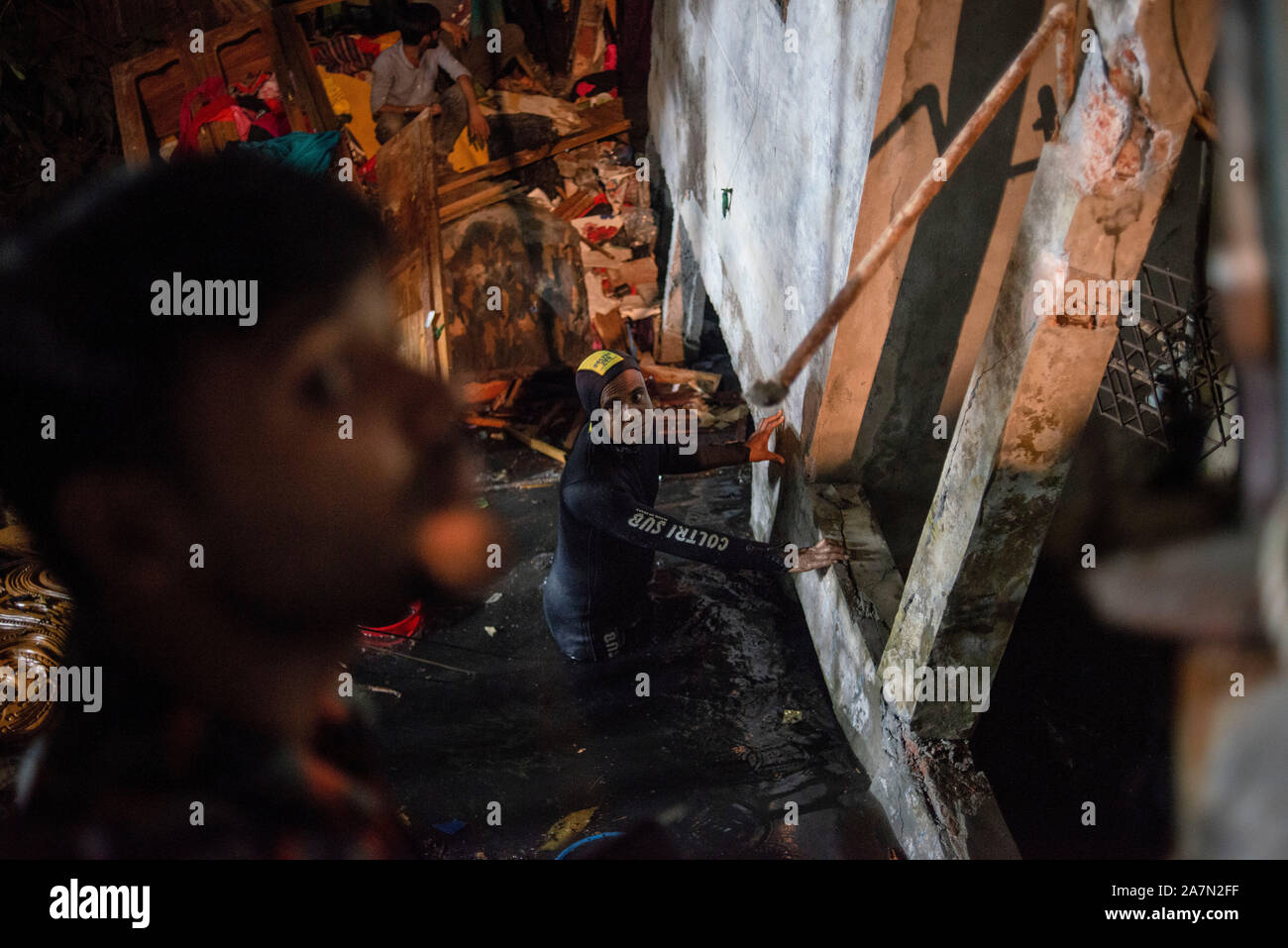 A member of the Fire and Rescue searching at the accident scene.A four storied building collapse beside it's pond in Narayanganj killing a 12 year old boy and one missing, 10 years old. Locals says the building was inappropriate. Stock Photo