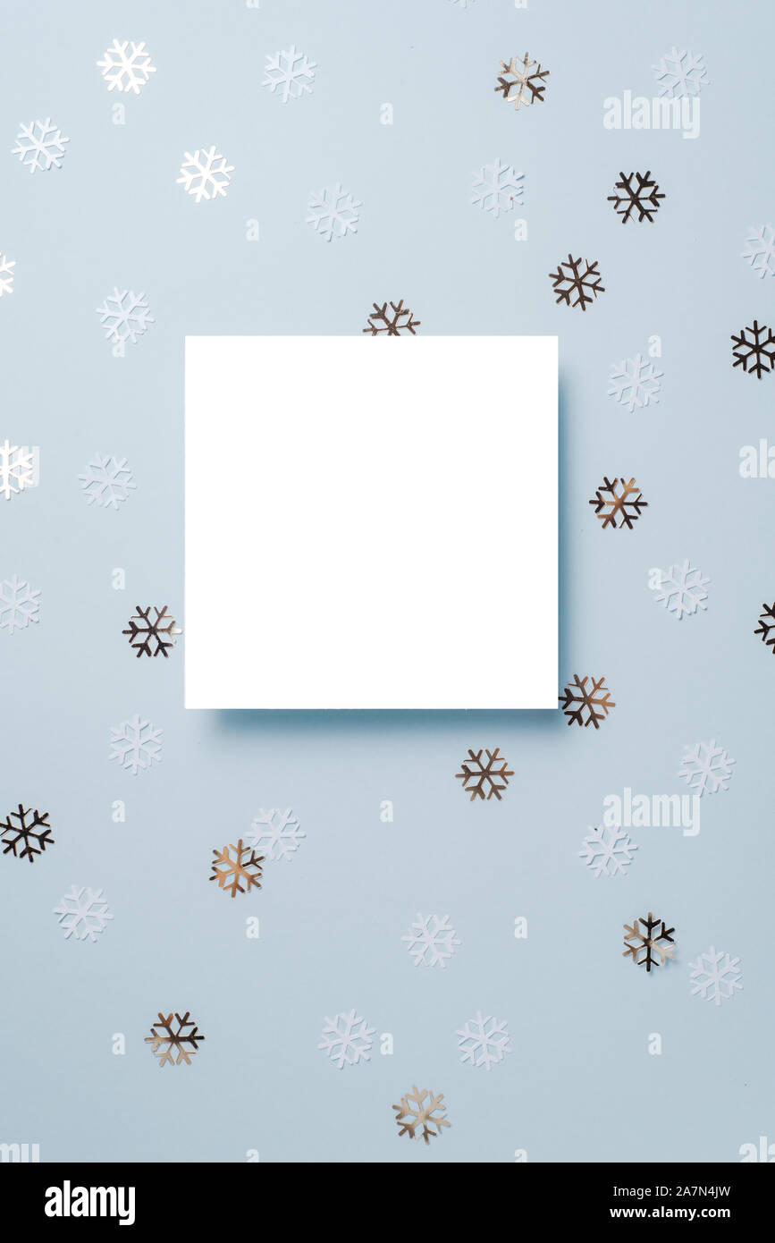White paper card decorated with snowflakes on blue background. New Year, Christmas and winter concept. Flat lay, top view, free copy space Stock Photo
