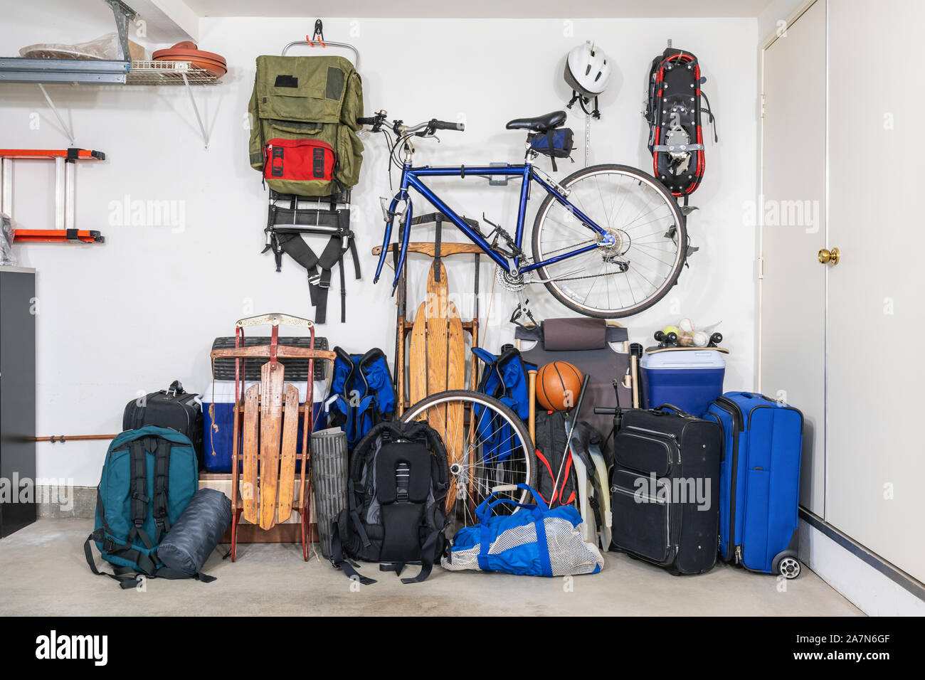 Sports and travel gear and equipment in piles in corner of messy