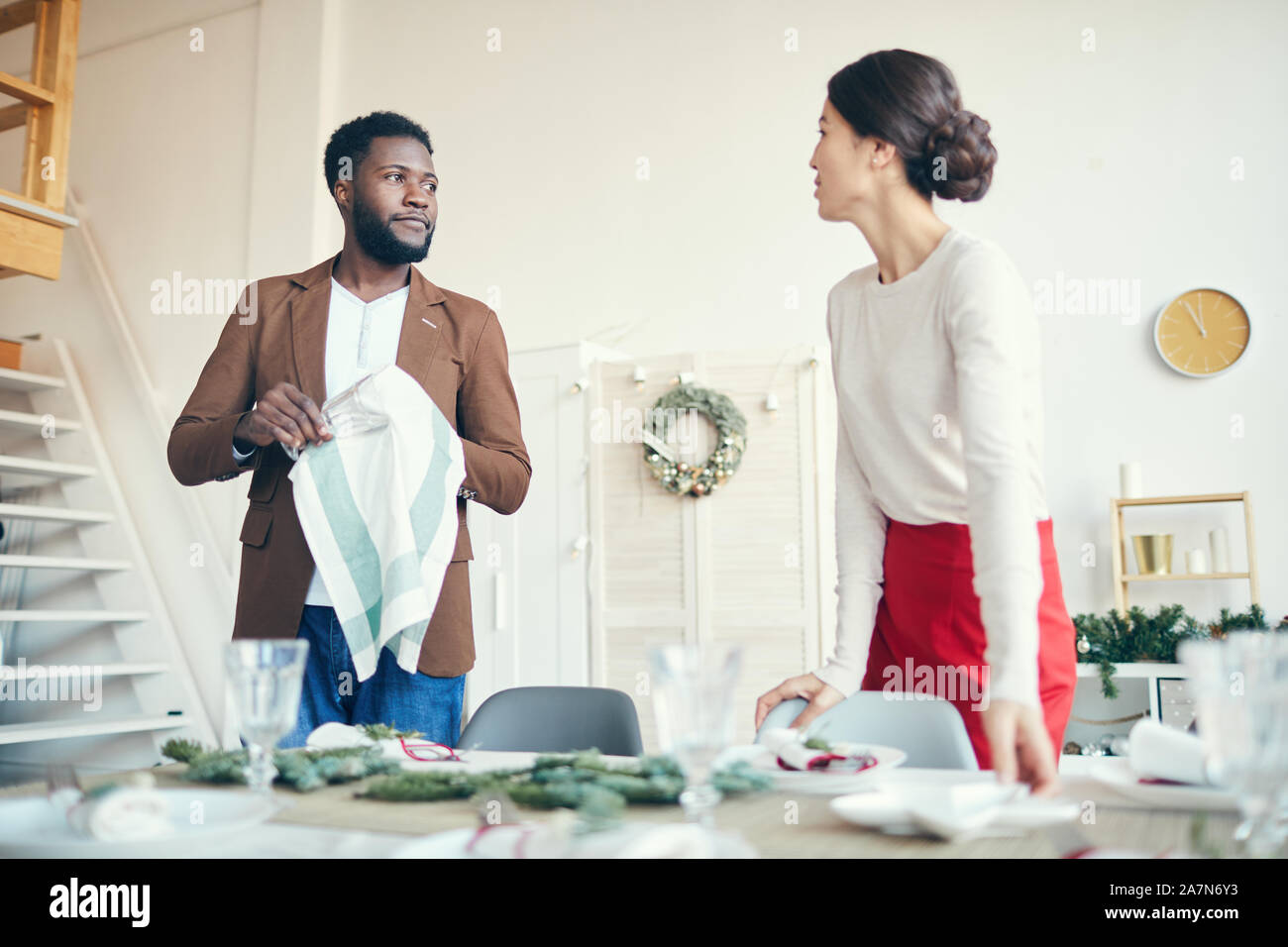 Portrait of modern young couple looking at each other while preparing for Christmas dinner party, copy space Stock Photo