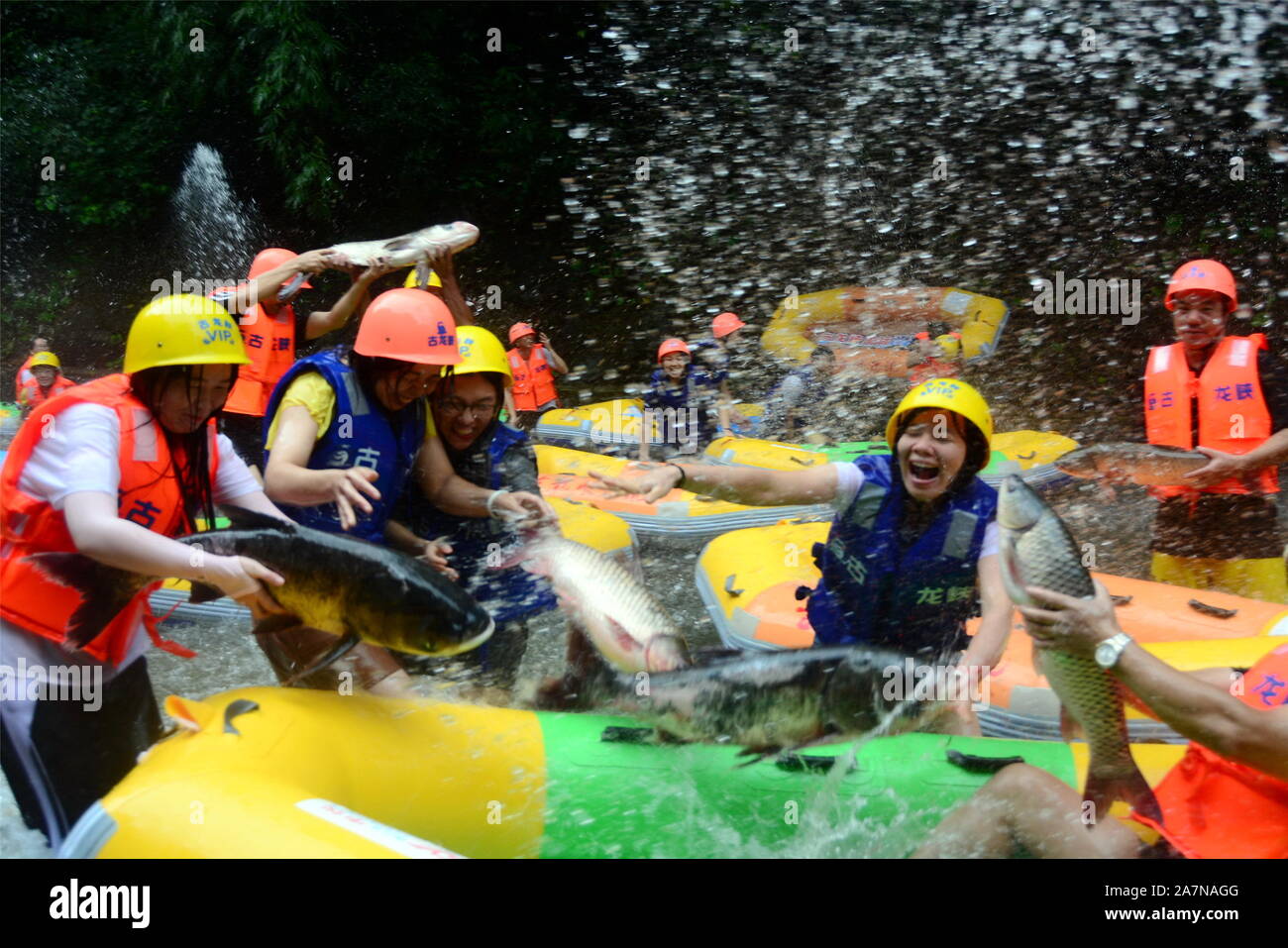 A crowd of tourists sitting on inflatable rafts jam a stream and catch ...
