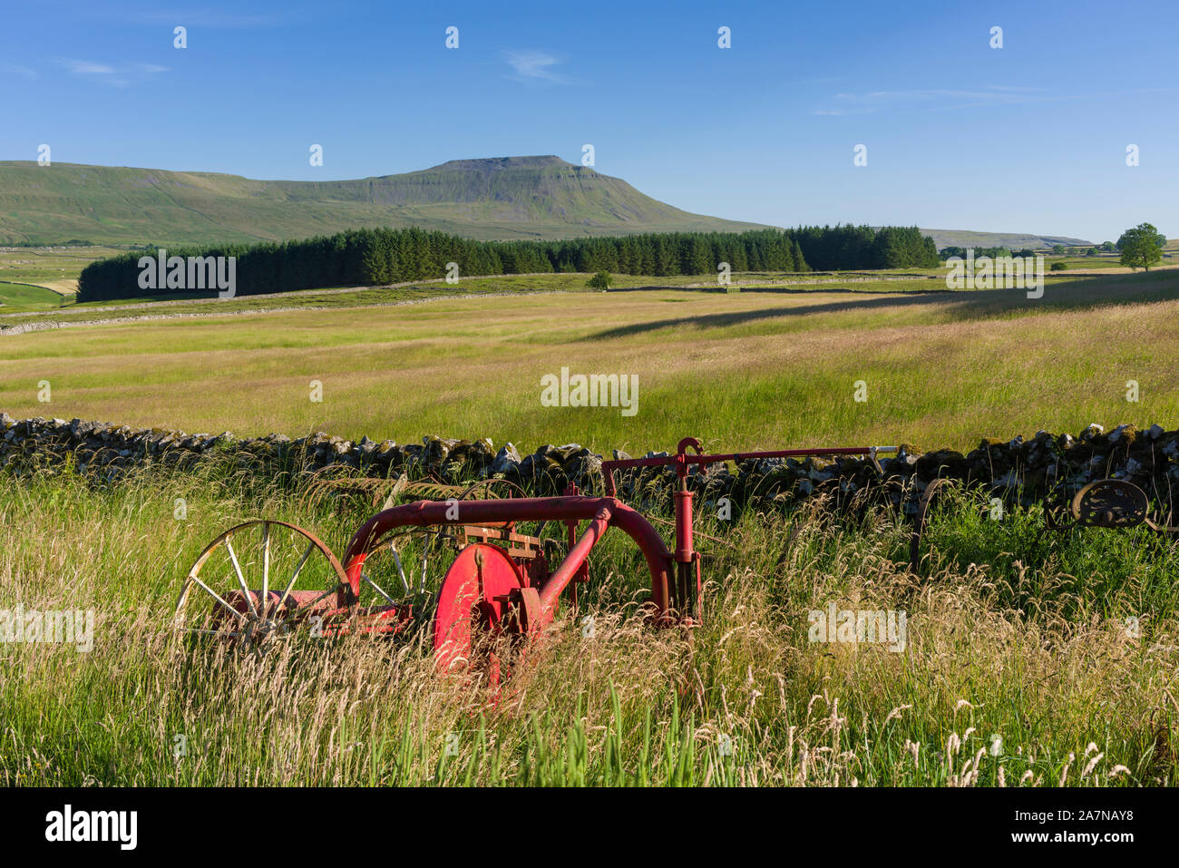 Farm machinery at the edge of a field in the Yorkshire Dales National Park with Ingleborough in the distance. Stock Photo