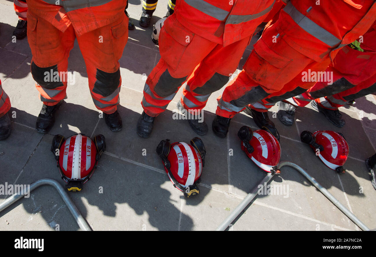 Firefighters and members of the Urban Search and Rescue team break for a moments silence before they continue to search for victims in the remains of Grenfell Tower fire disaster in North Kensington, West London. The fire was the deadliest domestic fire since the second world war. The fire broke out in the 24 storey block of flats just before 1:00am on the 14th June 2017 causing 72 deaths and injuring more than 70 people. Stock Photo