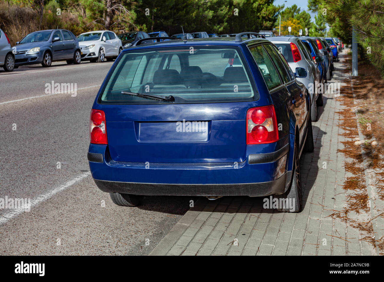 Cars or automobiles parked over the curb into sidewalk, leaving no space for pedestrians in the walkway. Road accessing a suburban railway. Illegal. Stock Photo