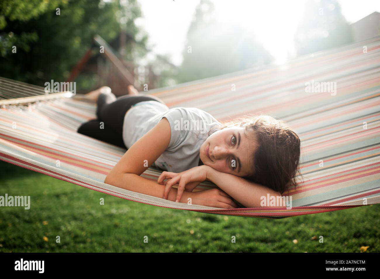 Tween girl looking while laying in hammock in backyard on spring day Stock Photo