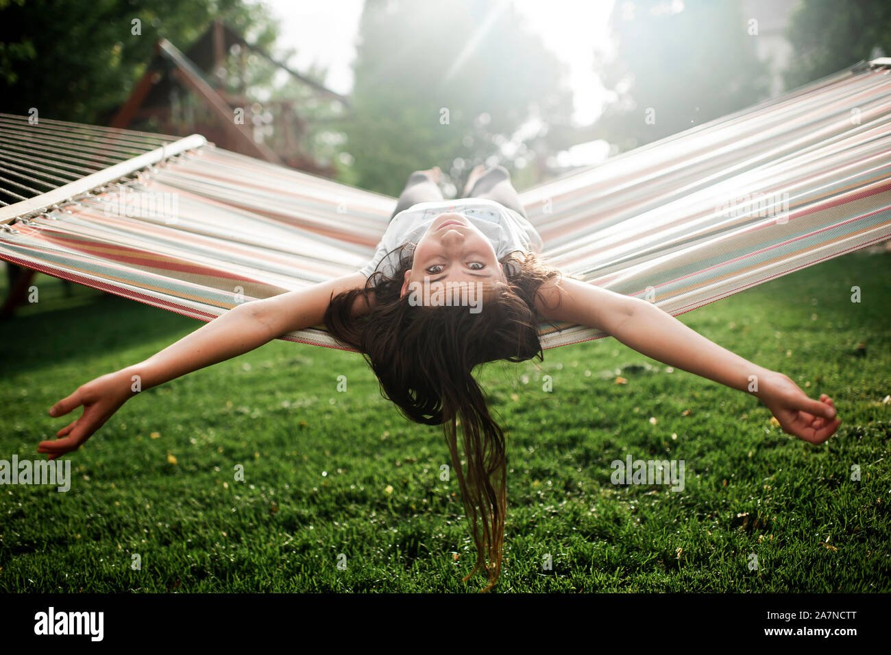 Tween girl taking a break while swinging in hammock in backyard Stock Photo