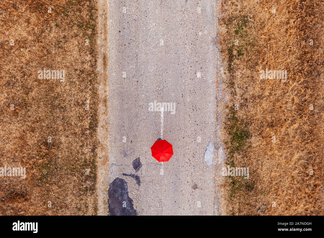 Red umbrella on road, top view from drone pov Stock Photo