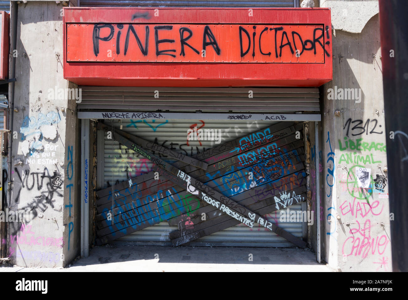 Damaged shop access in Santiago de Chile after the demostration, with grafitti and welded steel bars on the shutters to prevent looting Stock Photo
