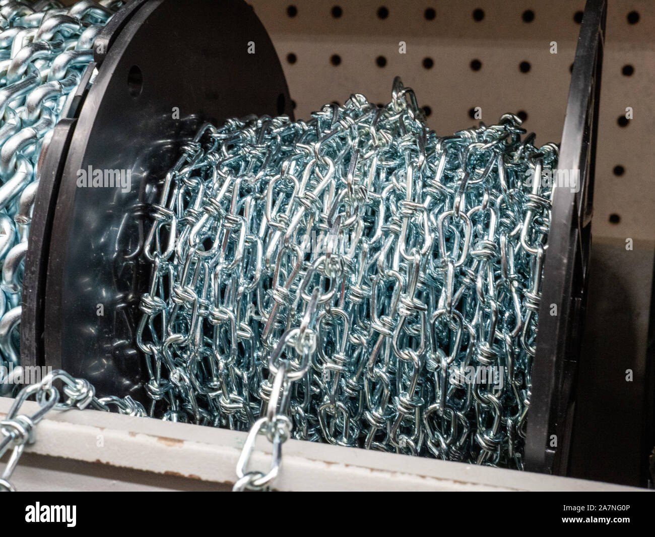 Roll of steel chain sitting in indoors storage area rolled up Stock Photo