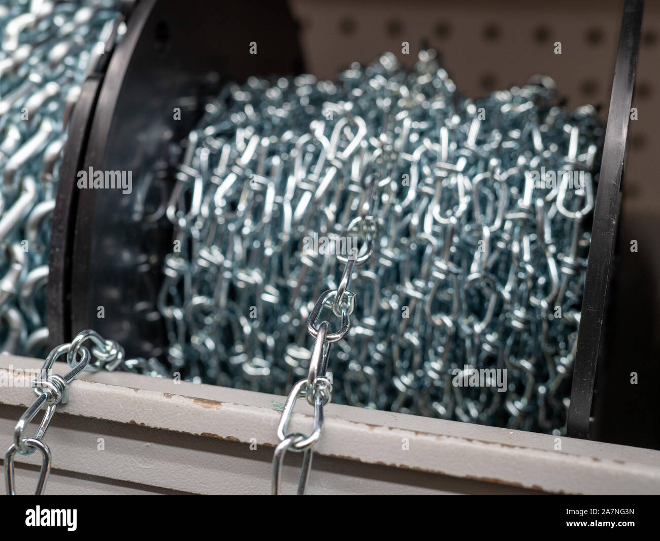 Roll of steel chain sitting in indoors storage area rolled up and spooled Stock Photo