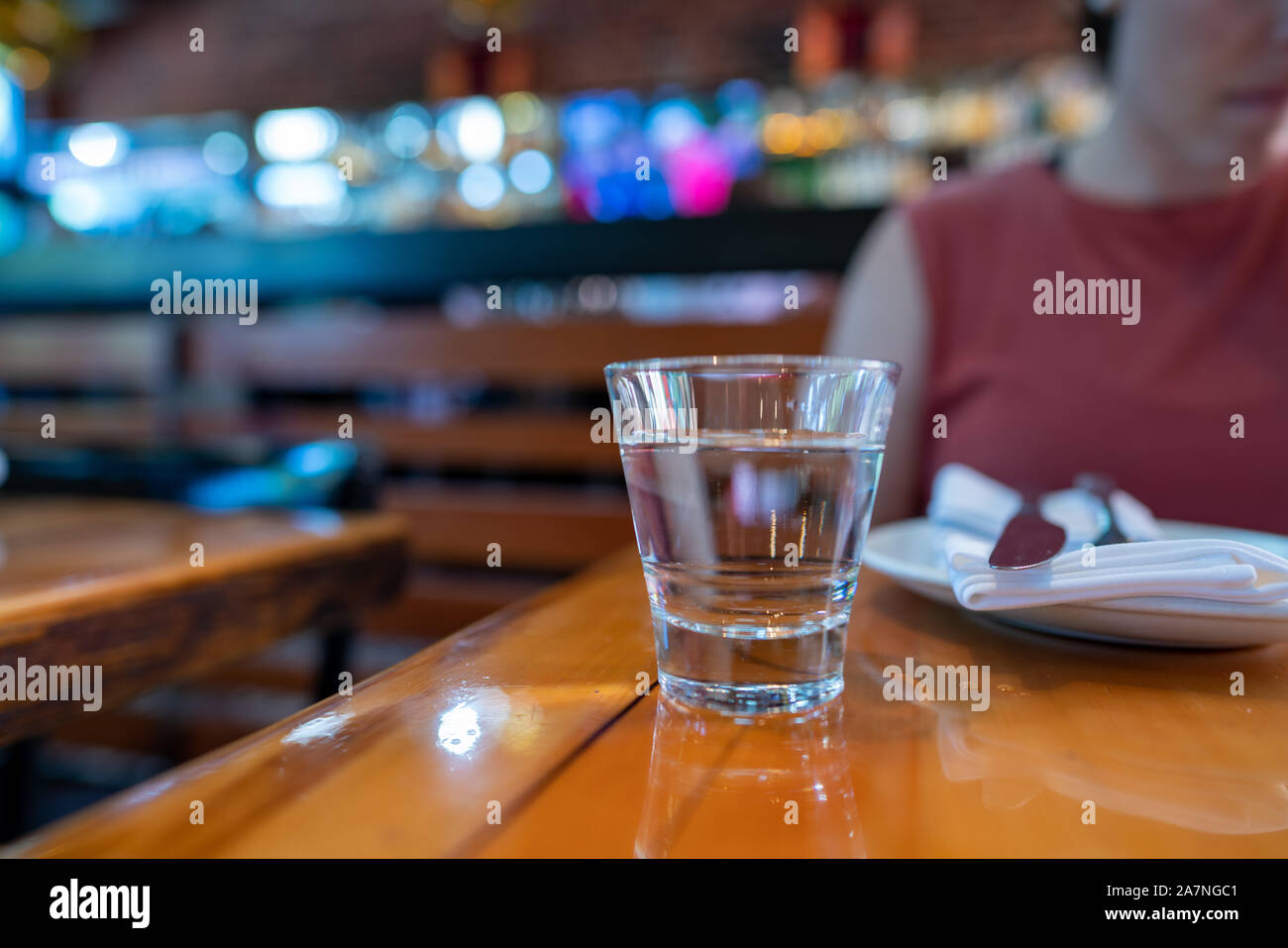 Glass of water in front of woman in dining restaurant table Stock Photo