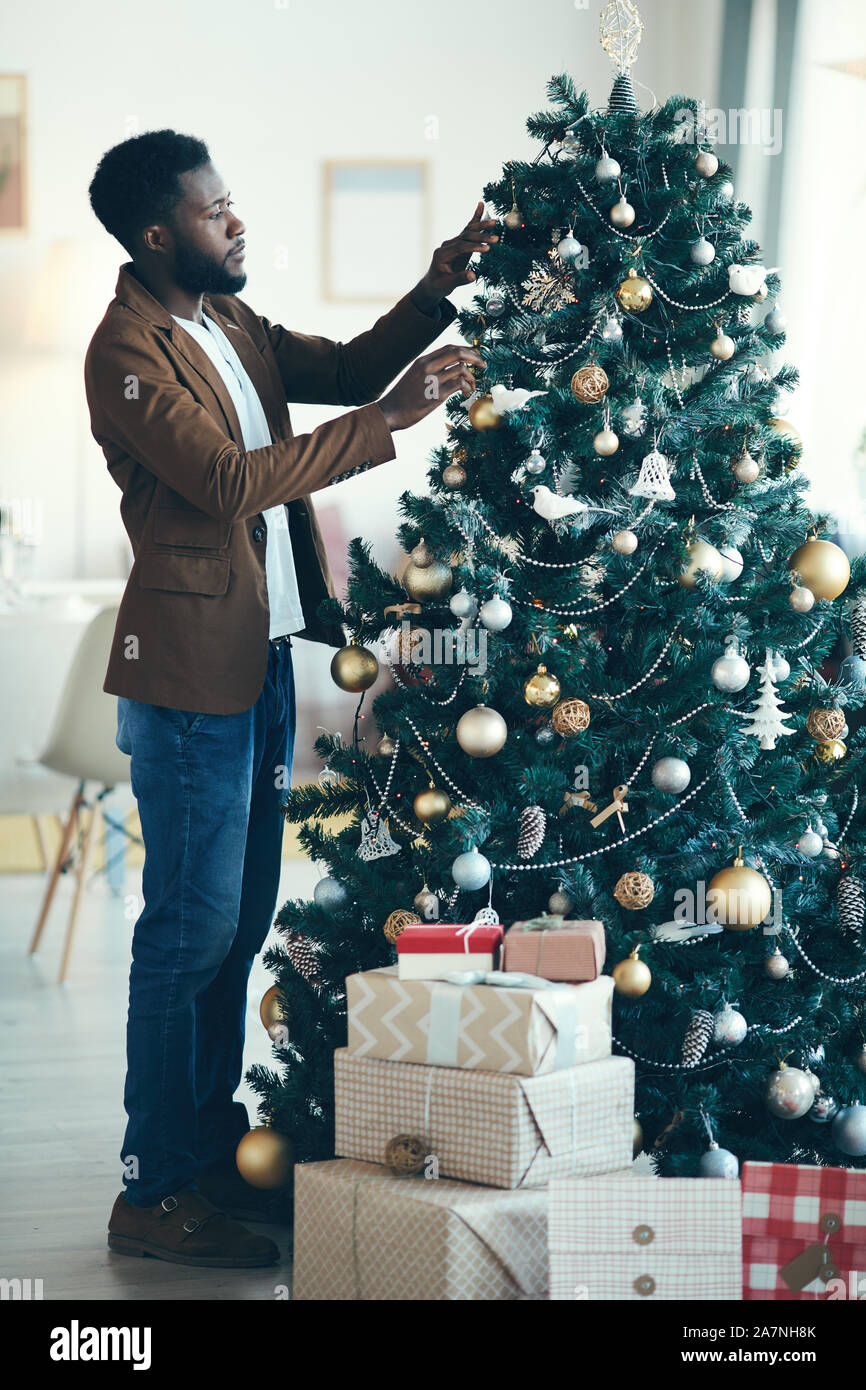 Full length portrait of modern African-American man decorating Christmas  tree at home, copy space Stock Photo - Alamy