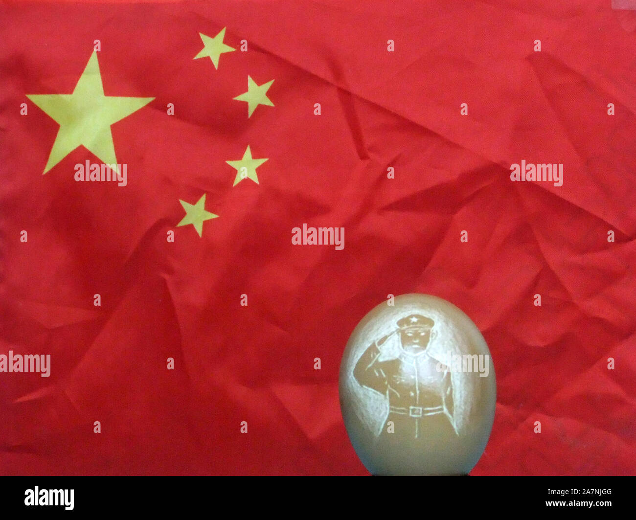 An egg shell painted with a soldier stands in front of a Chinese flag in Kaifeng city, central China's Henan province, 29 August 2019. A 70-year-old c Stock Photo