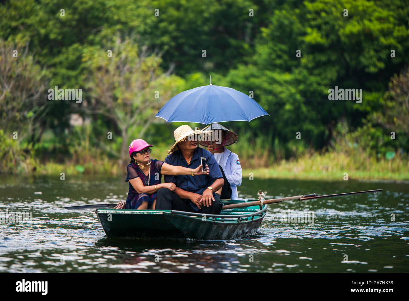 Tam Coc, Vietnam, 16th October 2019: Asian tourists travel on a rowing boat tour through the limestone caves of Ninh Binh on a sunny day Stock Photo