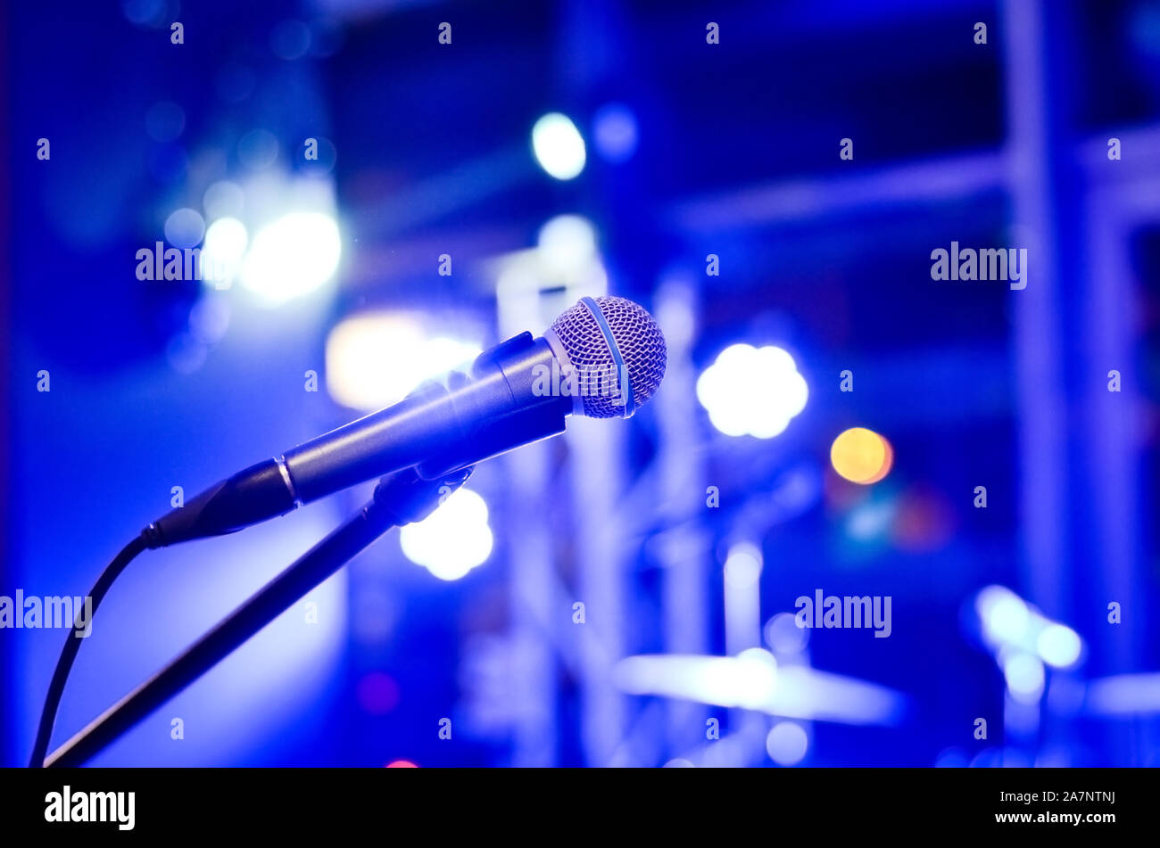 Close-up  of microphone on  empty  stage  with multi colored   blurred  background  lights     at a concert . Stock Photo