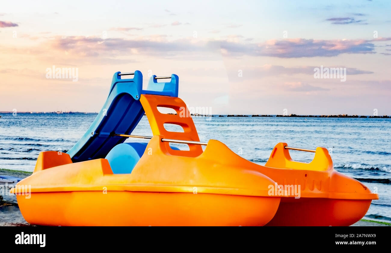 Beach paddle orange boats during summer season parked by the seashore