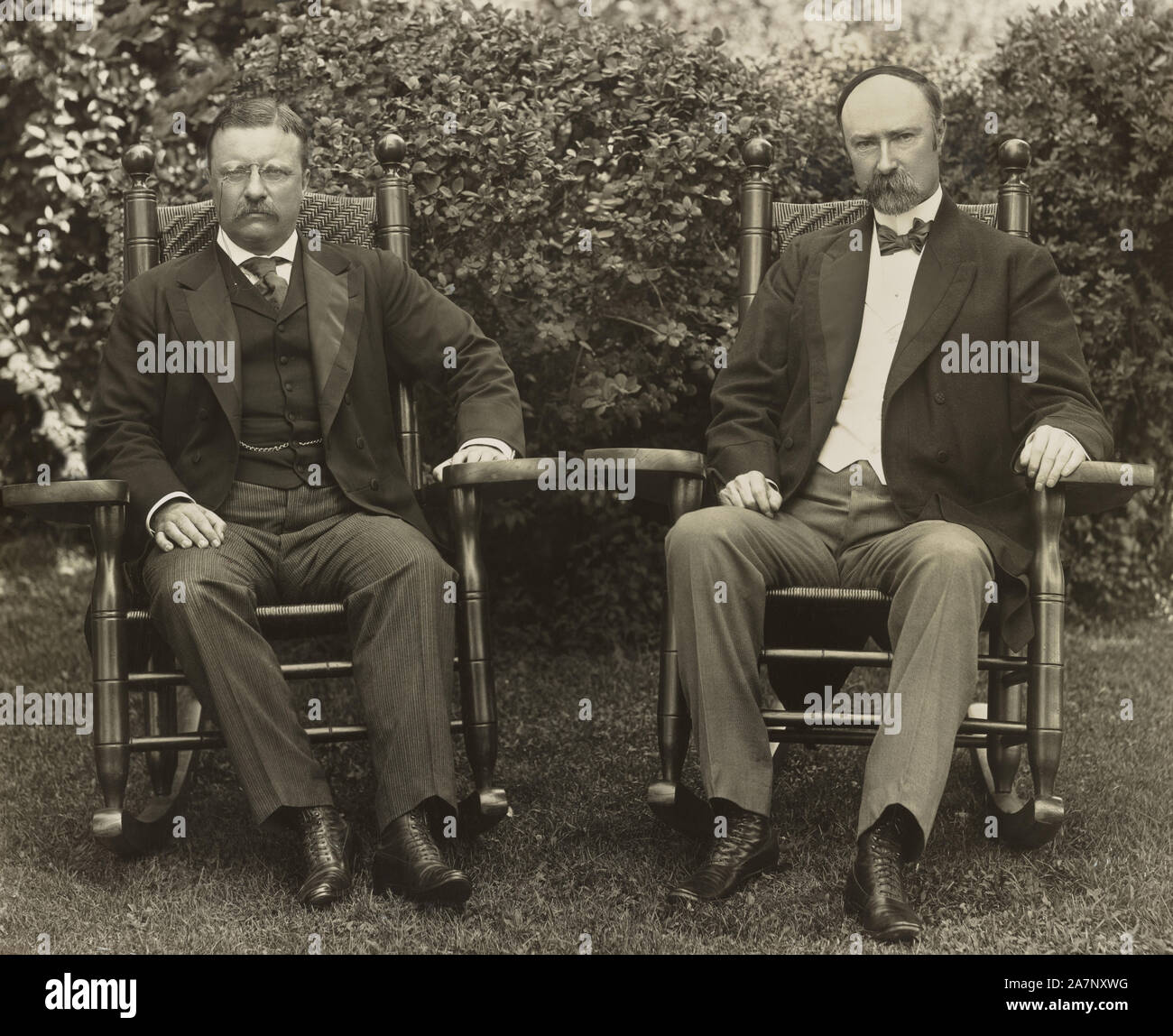 U.S. President Theodore Roosevelt and Vice President Charles Fairbanks, seated in rocking chairs, facing front, on lawn at Sagamore Hill, Cove Neck, New York, USA, Pach Brothers, 1904 Stock Photo