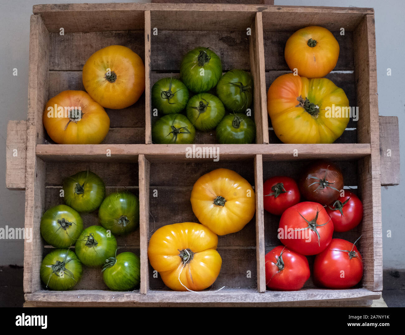 Wooden crate with a variety of different types of tomatoes in different