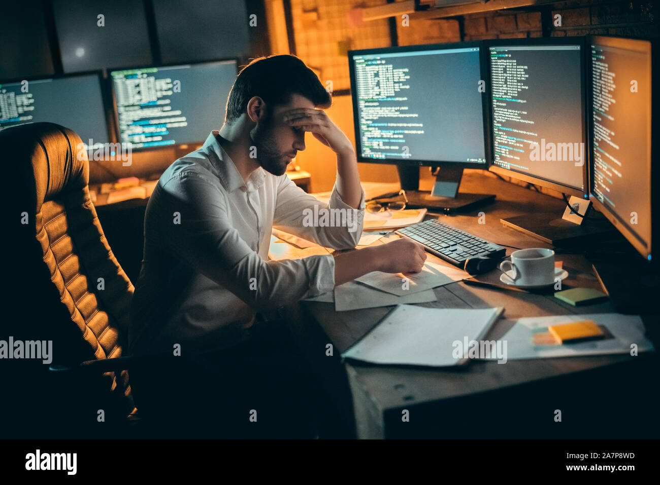Young male trader at office work concept sitting tired. Stock Photo