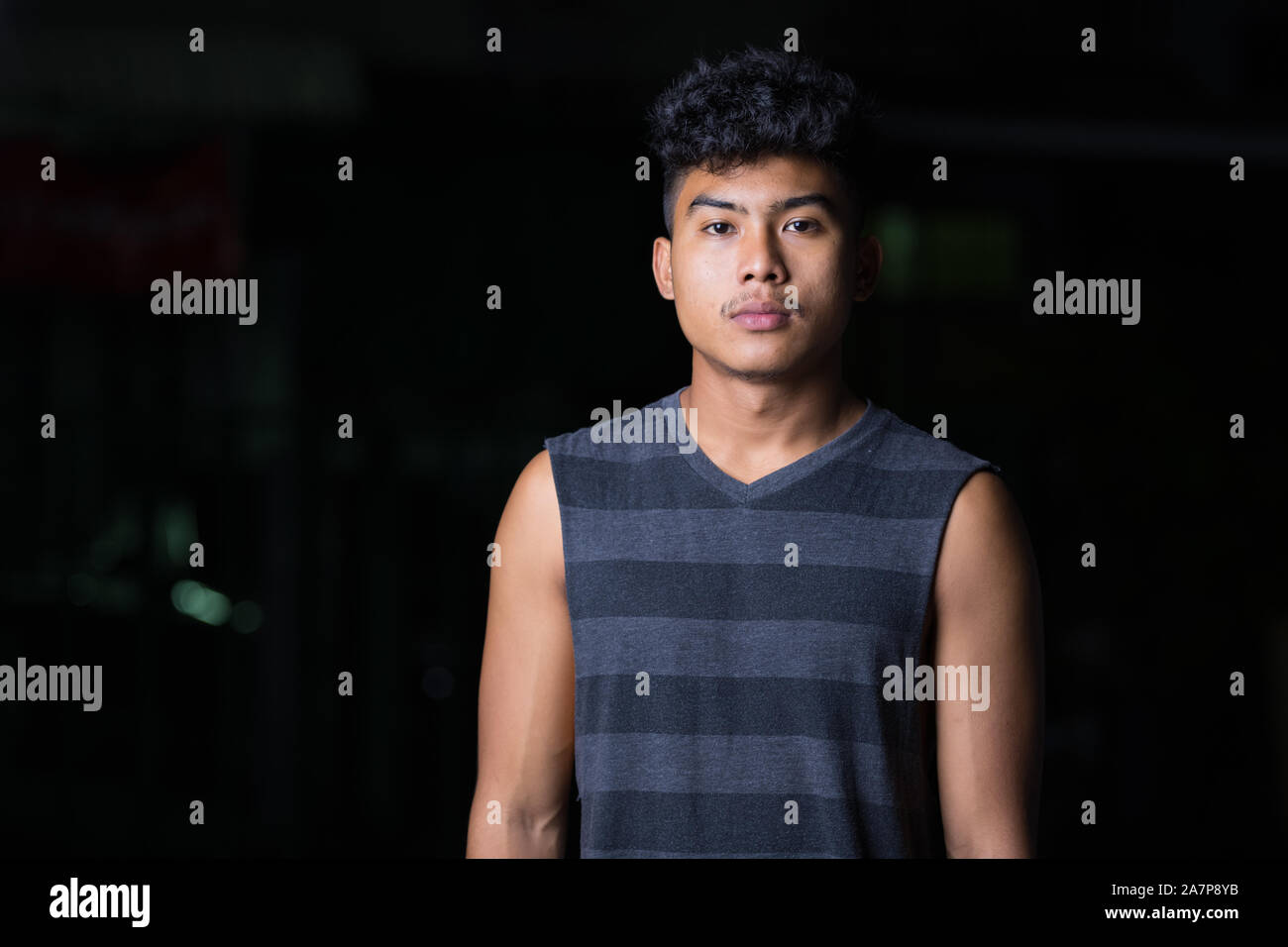 Young Asian man looking at camera at night outdoors Stock Photo