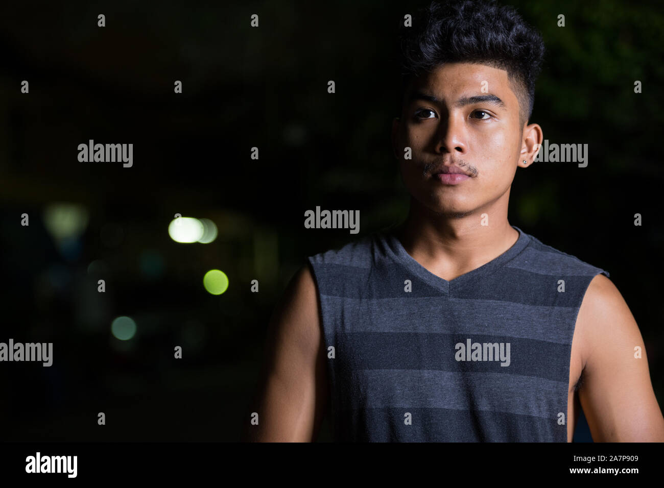 Face of young Asian man thinking at night outdoors Stock Photo